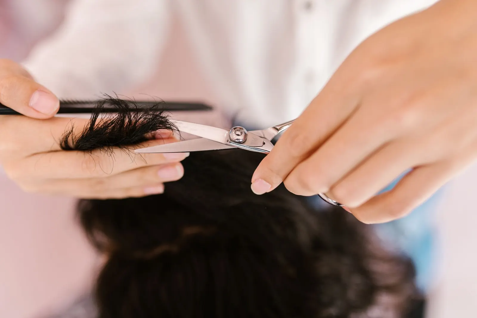 Mains du coiffeur coupant les cheveux aux ciseaux